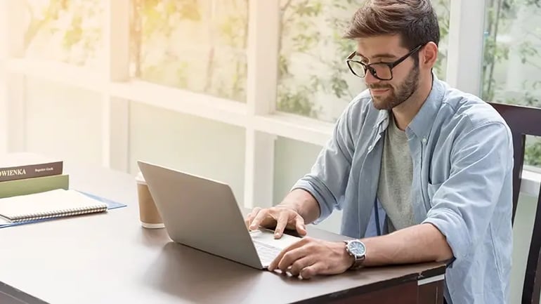 A MAN LOOKING AT A CHART OF FEDERAL INCOME TAX BRACKETS ON HIS LAPTOP.