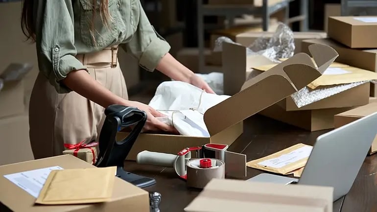 AN IMAGE OF A WOMAN PACKING BOXES, REPRESENTING THE IMPORTANCE OF SALES TAX FOR SMALL BUSINESSES. 