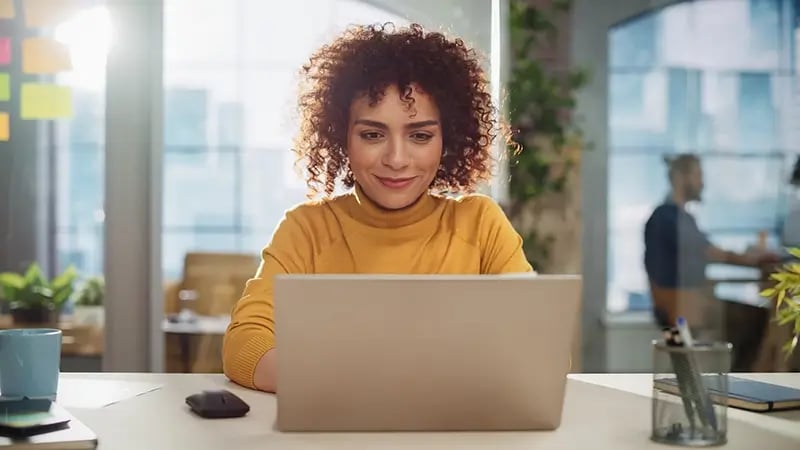 A PERSON USING A LAPTOP TO FILE THEIR TAXES ELECTRONICALLY, WITH A DIRECT DEPOSIT BANK ACCOUNT OPEN IN THE BACKGROUND