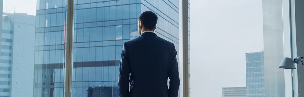 Um CEO observando a cidade pela janela de um prédio corporativo