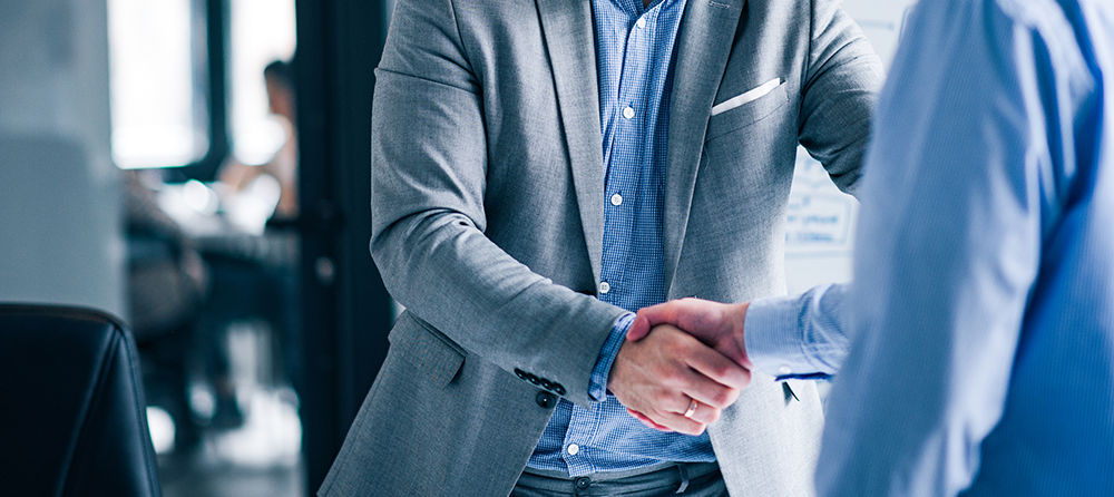 Duas pessoas apertando as mãos em um cenário corporativo