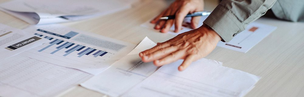 Imagem de uma mão pegando documentos de uma mesa