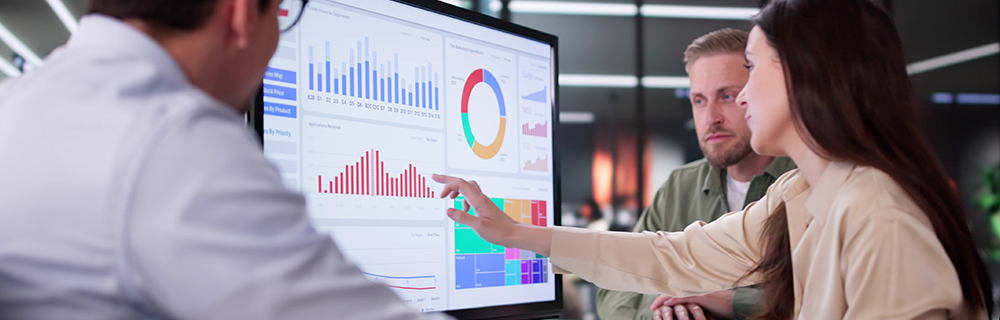 Pessoas analisando gráficos em uma tela grande
