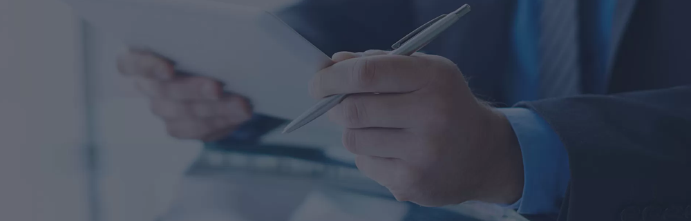 Uma pessoa lendo um documento com uma caneta na mão