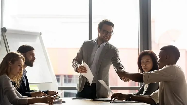 AN IMAGE OF A TAX PROFESSIONAL HELPING A GROUP OF PEOPLE WITH THEIR ACCOUNTING NEEDS.