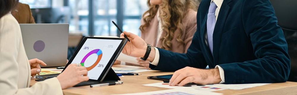 Imagem de uma executiva dando uma explicação para um cliente, utilizando gráficos