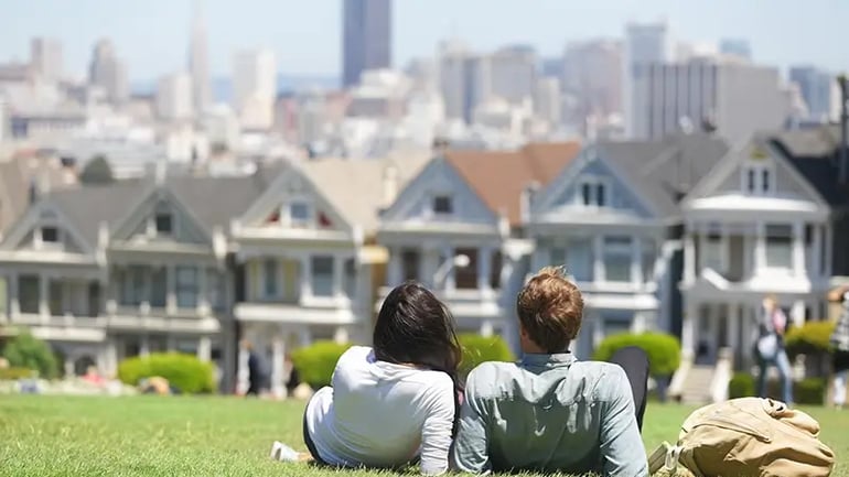 A COUPLE SITTING ON THE GRASS WHILE VIEWING PROPERTY IN SAN FRANCISCO, CALIFORNIA.