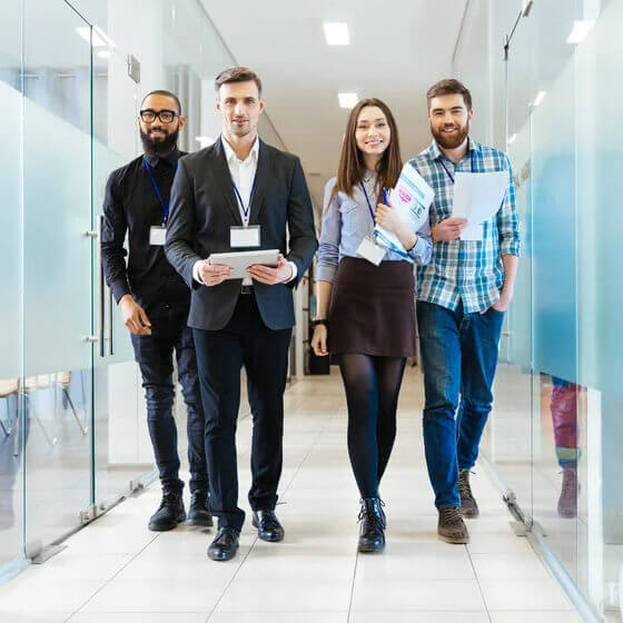 Full length of group of happy young business people walking the corridor in office together