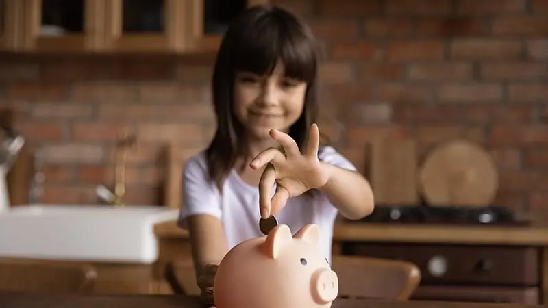 Una niña de cabello negro ahorrando dinero representando el impuesto sobre la renta