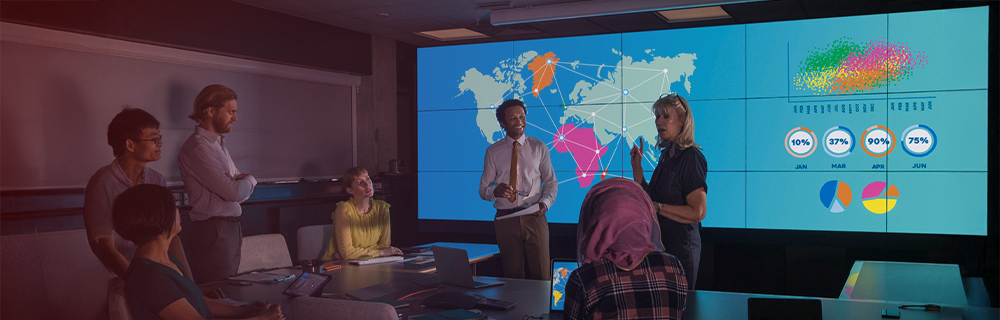 Imagem de uma equipe de consultores estratégicos em reunião, com um mapa-múndi e gráficos ao fundo