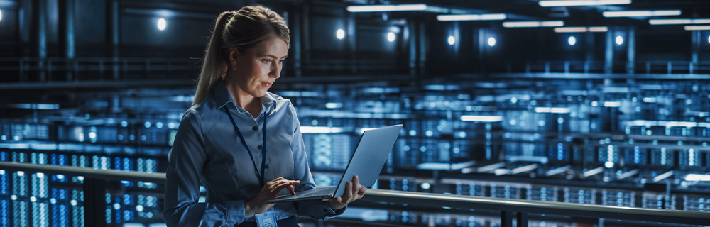 Imagem de uma profissional mexendo em um notebook numa estrutura de TI