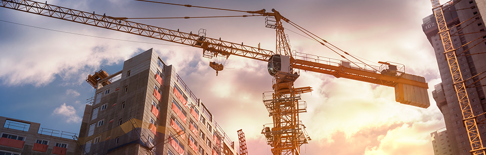 Imagem de um guindaste e um prédio sendo construído